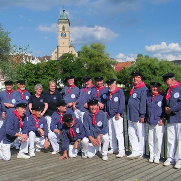 Shanty-Chor steht vor Fluss und Kirche