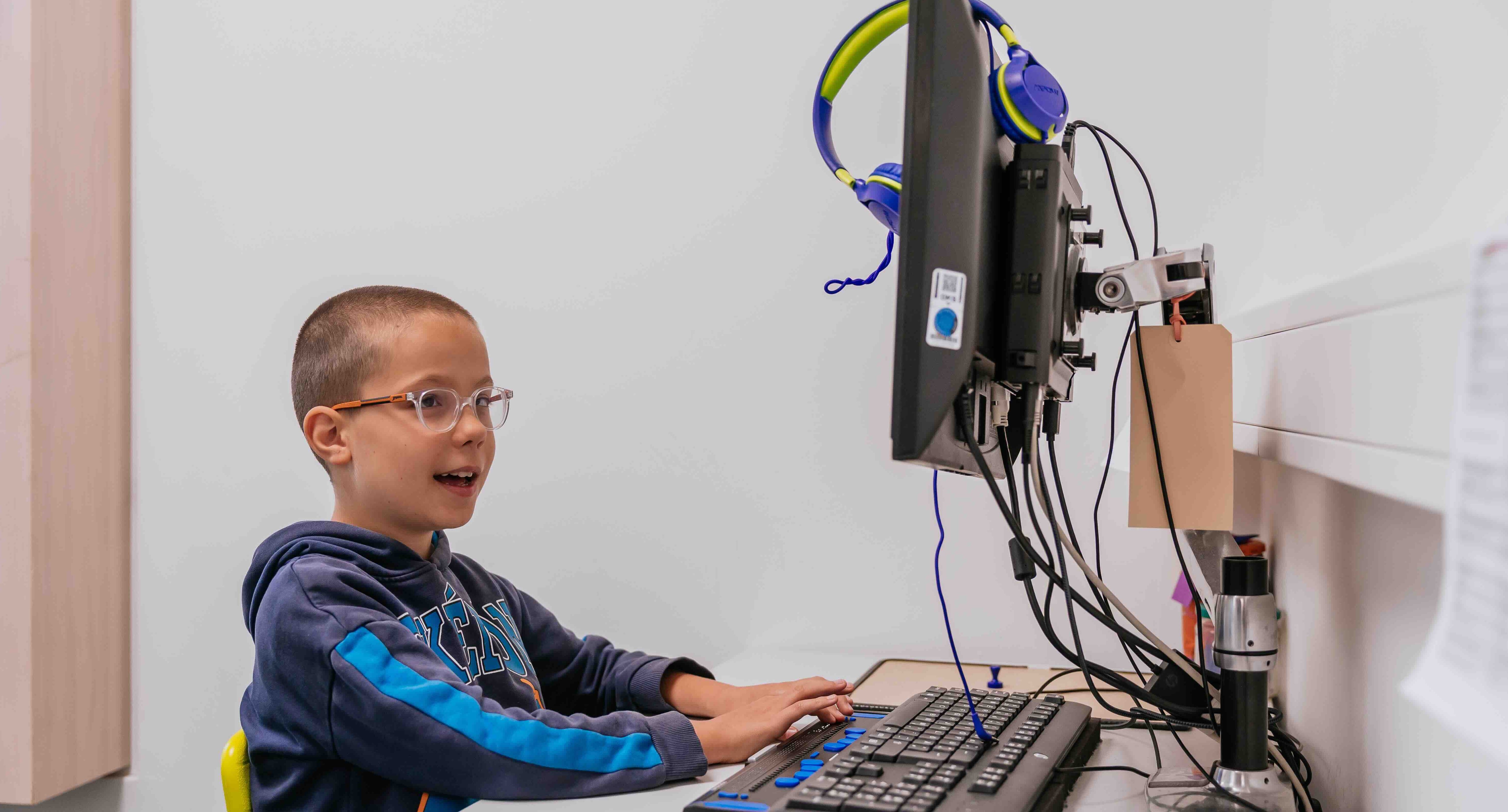 Michail sitzt am Computer und schreibt mit der Computerbrailleschrift.