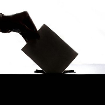 Schwarz-weiß Bild einer Hand, die einen Brief in eine Box einschiebt.