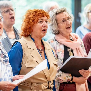 Eine Gruppe von älteren Frauen singt zusammen in einem Chor.