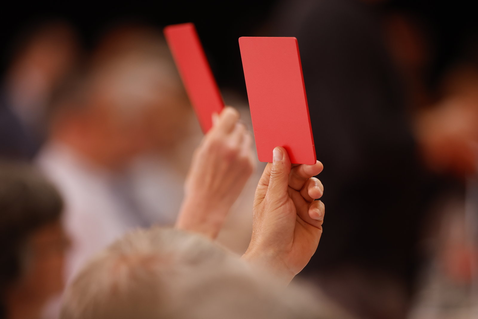 Rote Abstimmungskarten werden in der Hand gehalten.