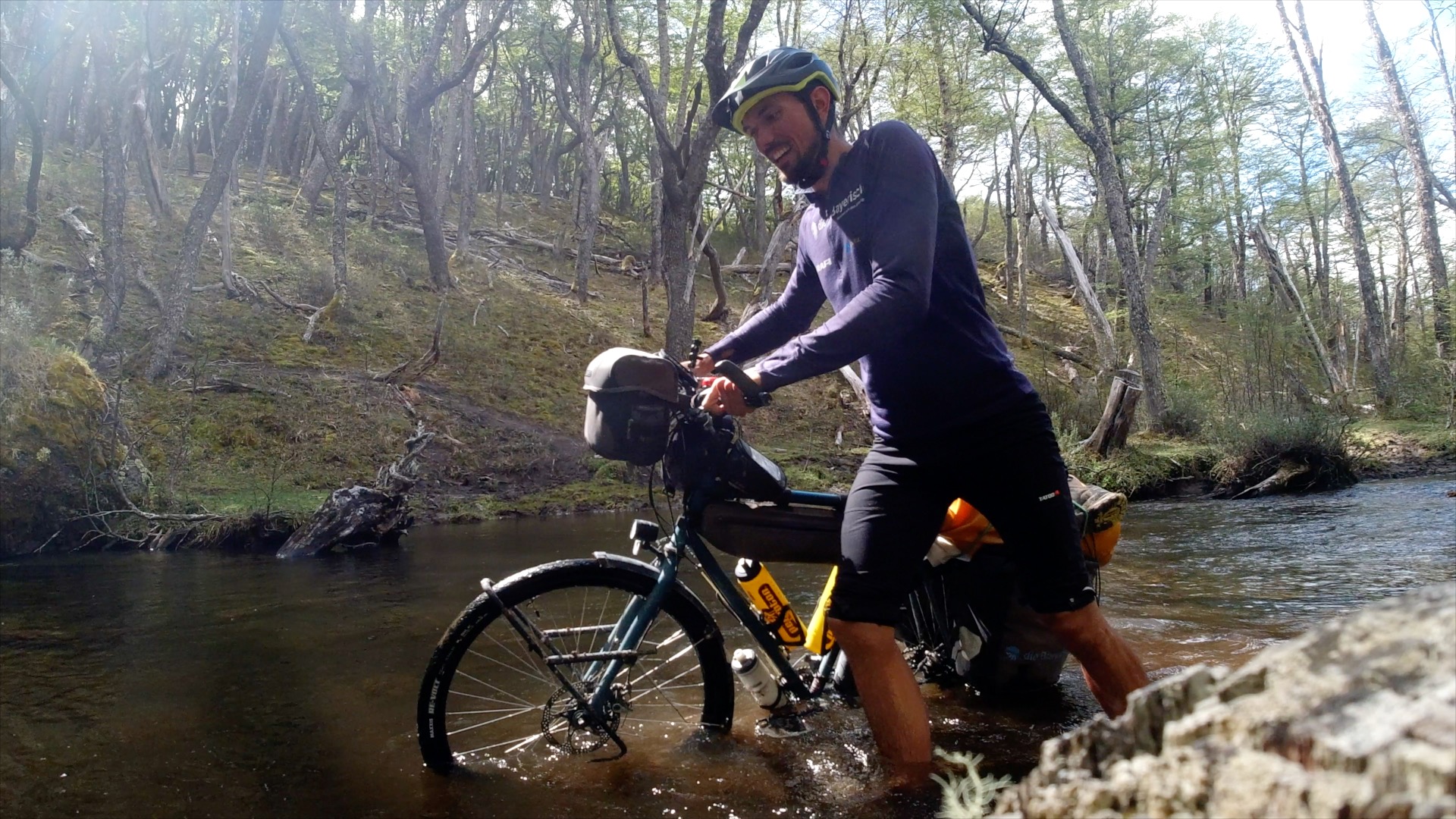Darius Braun watet mit dem Fahrrad durch einen Bach in Patagonien