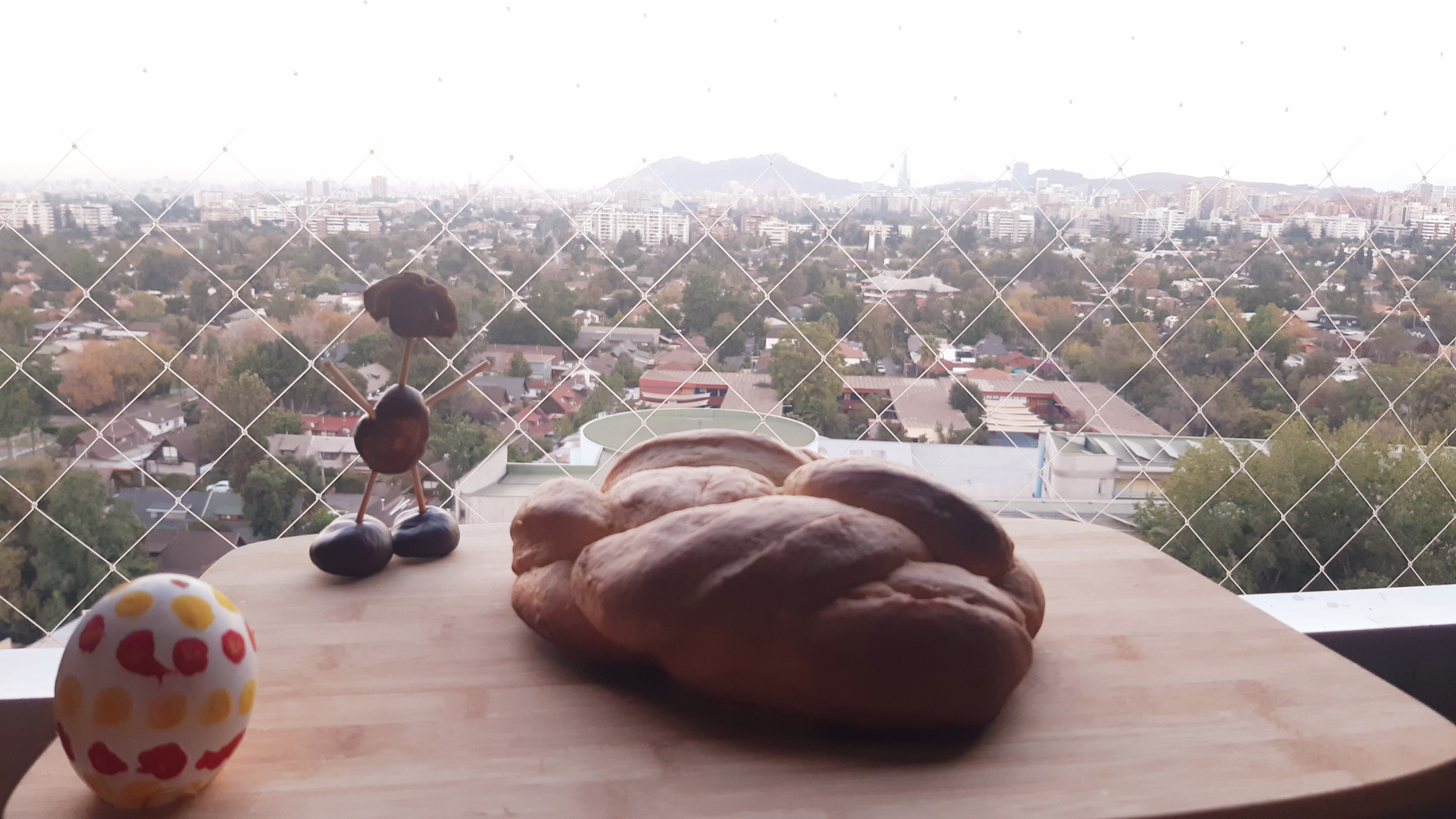 Fenster über einer Stadt. Auf einem Brett liegt ein Hefezopf.