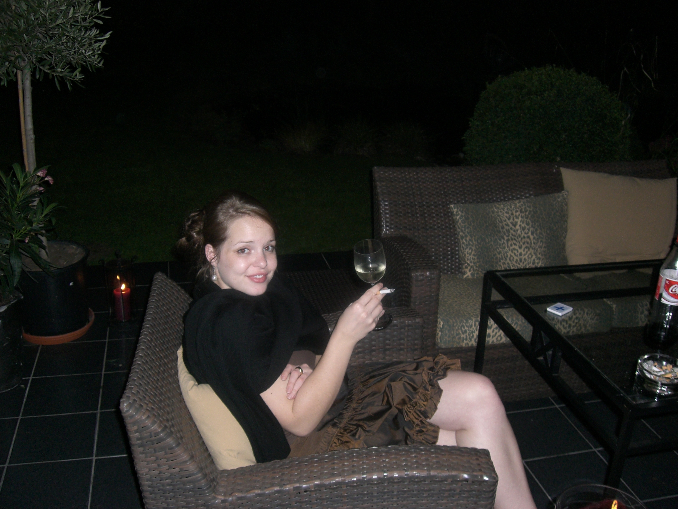 Nathalie Stüben sitzt auf einer Terrasse mit einem Glas Wein und einer Zigarette in der Hand.