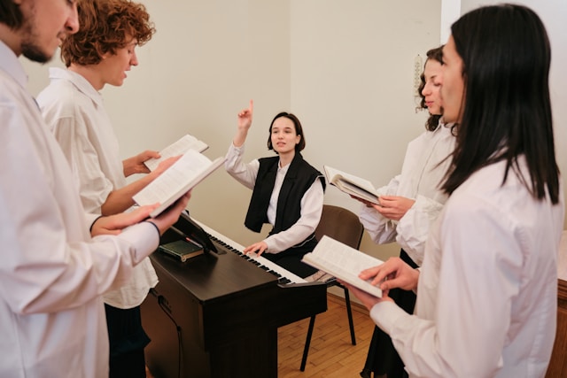 Eine Gruppe von Menschen singt gemeinsam. Eine Frau sitzt an einem Klavier