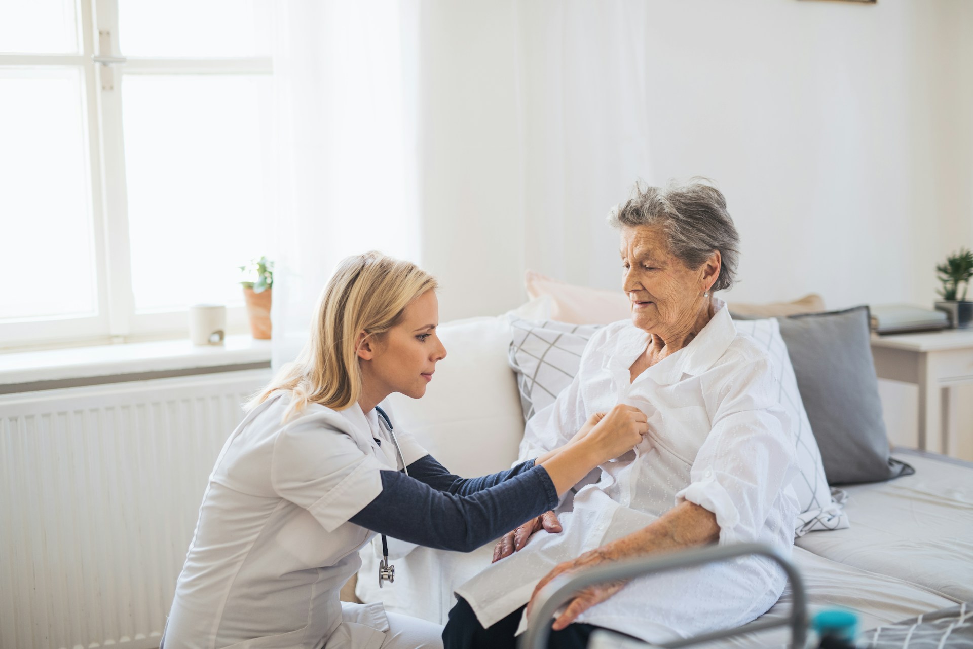 Pflegekraft hört Seniorin mit Stethoskop ab.