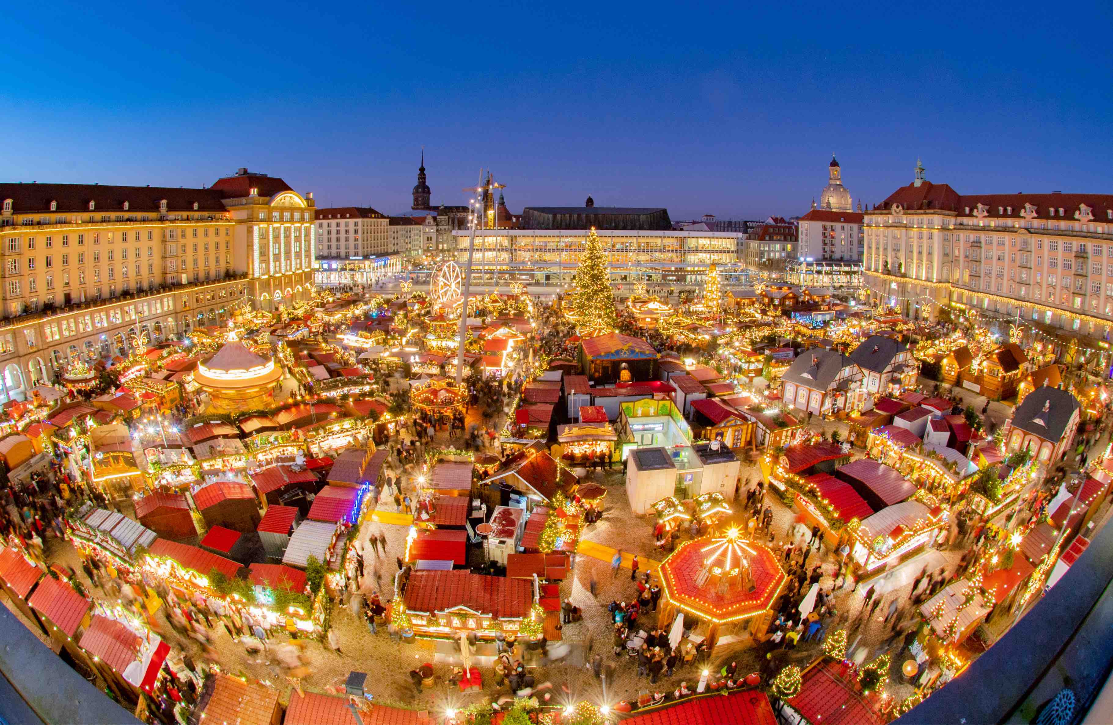 Luftbild vom Dresdener Striezelmarktes bei Dunkelheit. Unten leuchten viele Lichter. Der Himmel ist dunkelblau. 